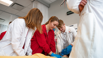 Nursing and medical students practice on a dummy in a lab.
