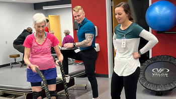 Two physical therapy students working with older woman in exercise room