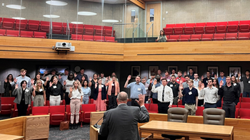 Chief Justice Steven R. Jensen administers the oath of professionalism to a crowd of 90 law students in a courtroom.