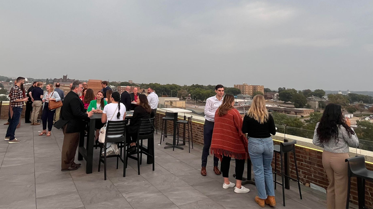 People stand around on a rooftop and mingle.