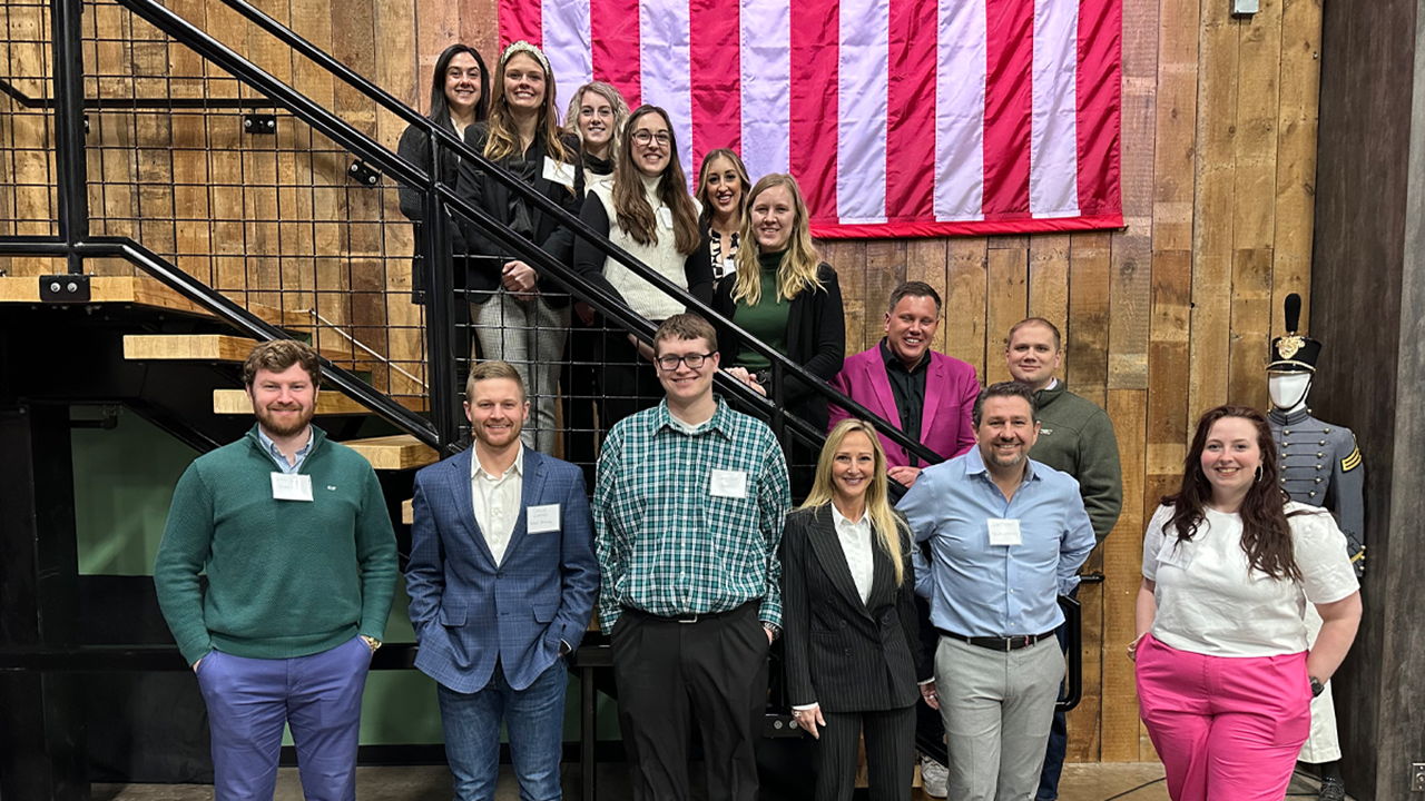A group of Veterans Legal Education Group participants stand on and in front of black stairs for a photo.