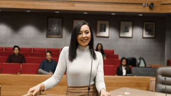 A law student stands at a podium in the Knudson School of Law courtroom, practicing for an argument.
