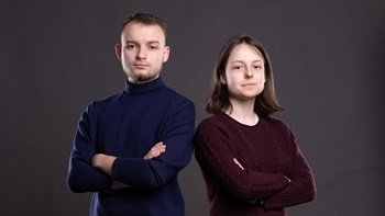 Anton Pratsenko and Sasha Lukina standing in front of gray wall