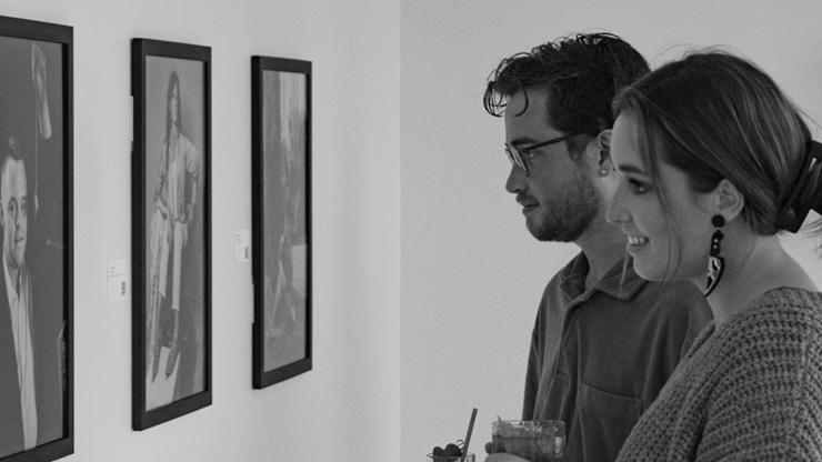 Two people look in awe at three framed images hanging on the wall at a photo exhibit.