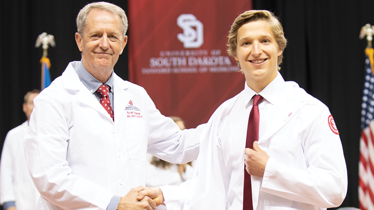 Andrew Nerland shakes hands with Dr. Tim Ridgway at the White Coat Ceremony.
