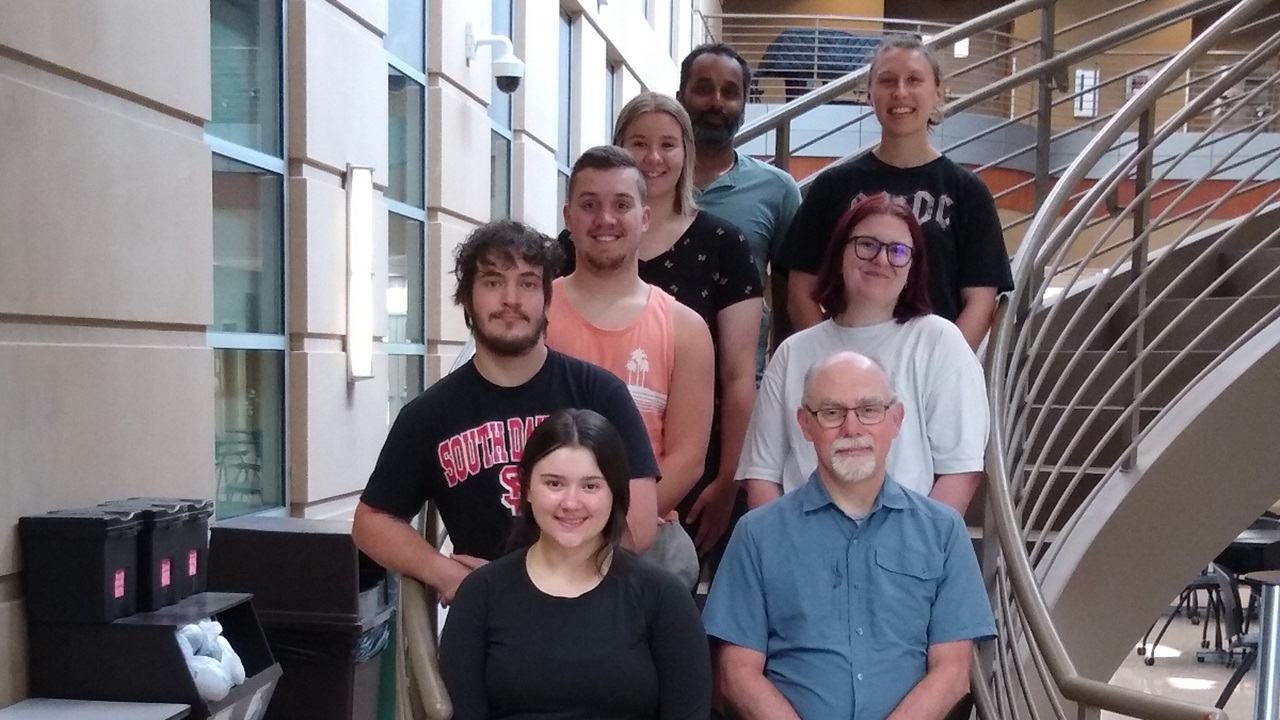 Maykala Mofle, Brian Burrell (SPURA Co-Director), Spencer Hurst, Tyson Junck, Sophia Van Bursick, Abigail Stelling, Yohann Fernandes (mentor), Morgan Rothschadl (peer mentor) standing on a staircase.