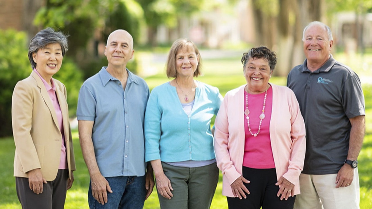 Five people over the age of 50 stand together outside. Five people over the age of 50 stand together outside.