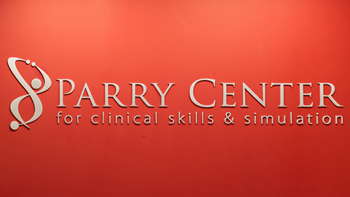A red wall with letters that say Parry Center for Clinical Skills & Simulation.