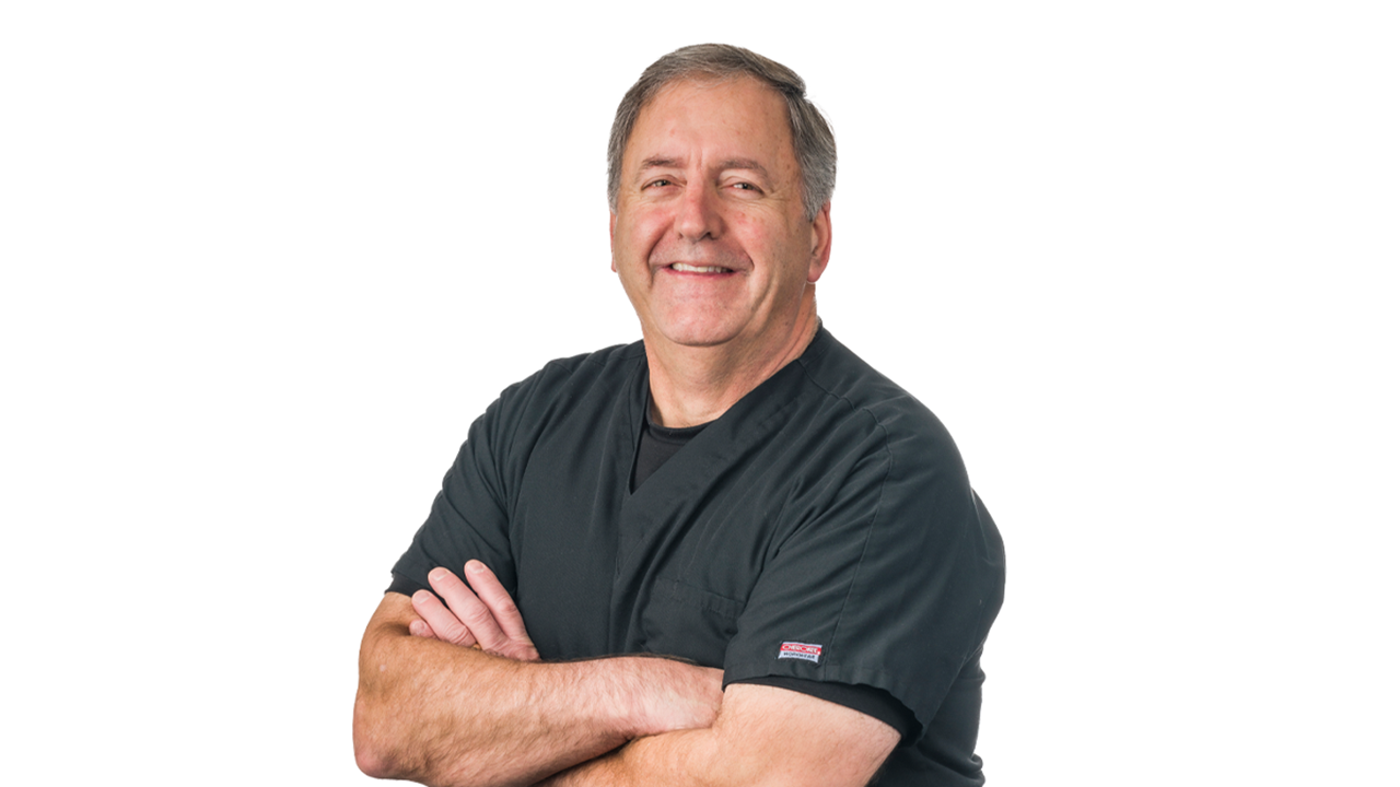 Vance Thompson stands with his arms crossed and smiles. He is standing in front of an all white background.