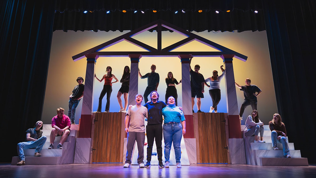 Theater students on stage standing in a set representing the Temple of Zeus.