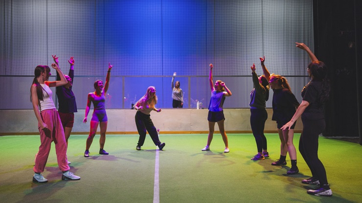 The Wolves 2024 A group of young women rehearse for a theatrical production set on the stage of a soccer field.