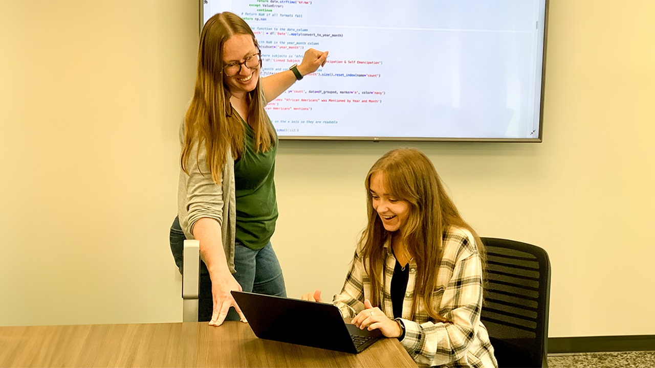 Lindsey Peterson helping someone, looking over a shared laptop. Lindsey Peterson helping someone, looking over a shared laptop.