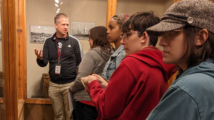 Nathan Bates talks about artifacts in a museum to his students.
