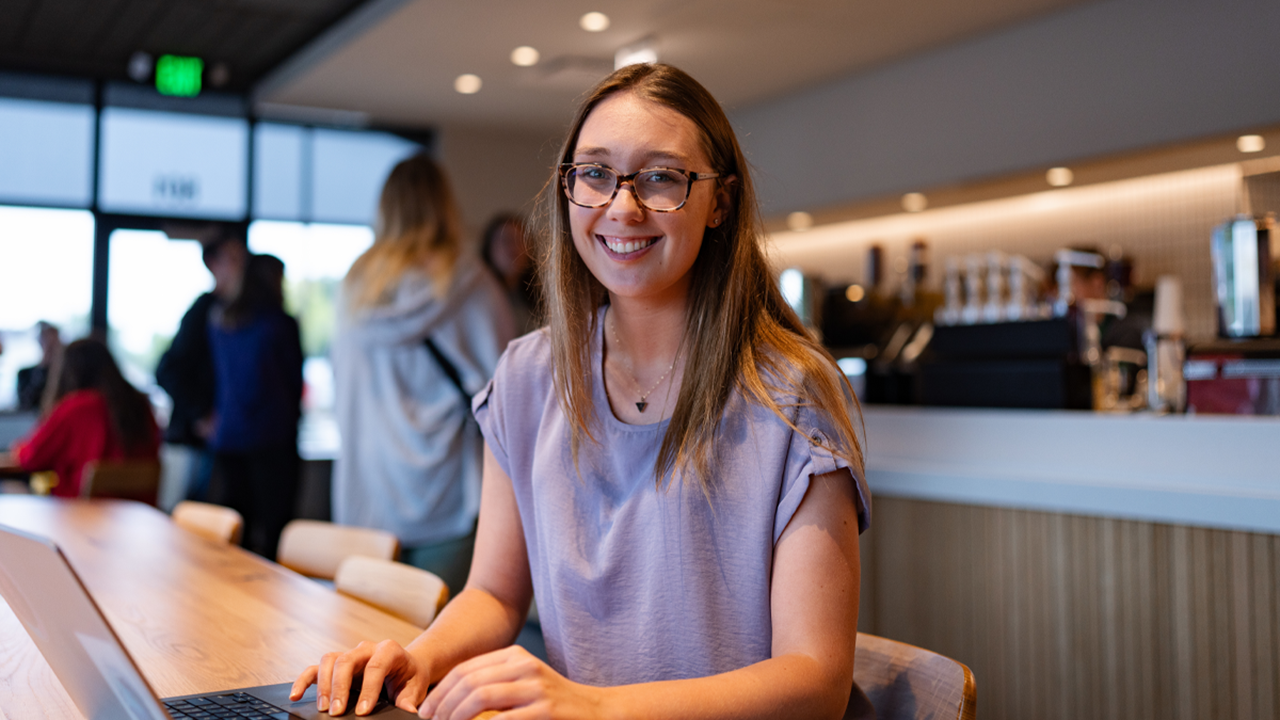 Jordan Grothe types on a laptop keyboard while looking at the camera for a photo.