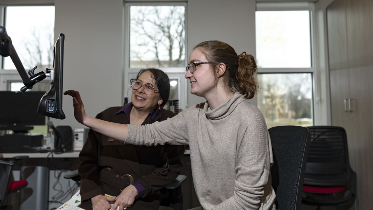 Elizabeth Hanson and a student look at a computer that displays speech communication assistance tools. Elizabeth Hanson and a student look at a computer that displays speech communication assistance tools.