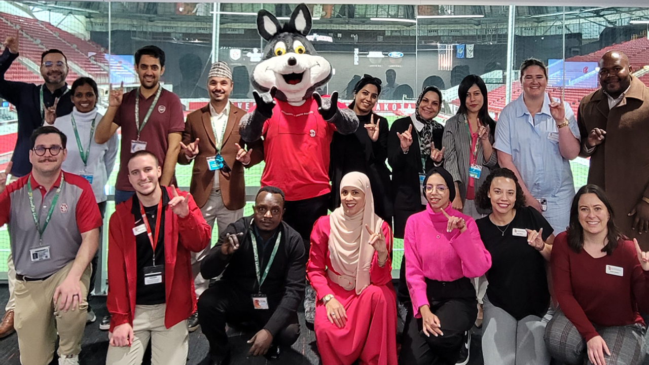 International high school guidance counselors and staff from USD's Gallagher International Center stand together for a photo with Charlie Coyote.