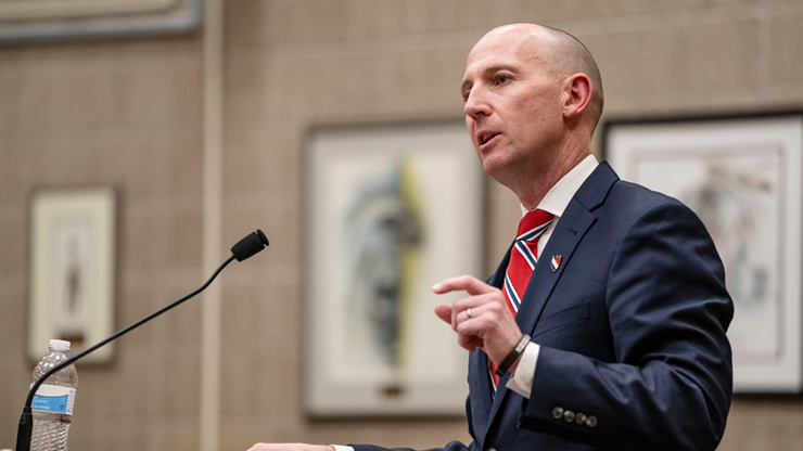 Dean Neil Fulton speaks passionately into a microphone at a stand in the law school courtroom.
