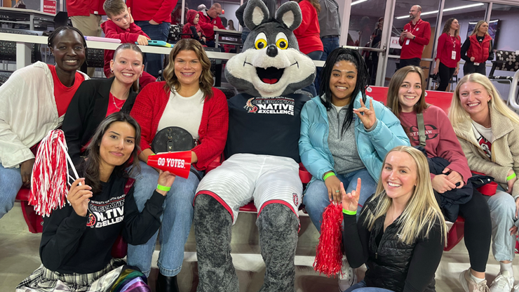 Law students and alumnae gather around Charlie Coyote for a photo in the Sanford Coyote Sports Center.