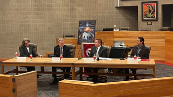 Four law professionals sit at a long wooden table during a panel discussion in the USD law school courtroom.