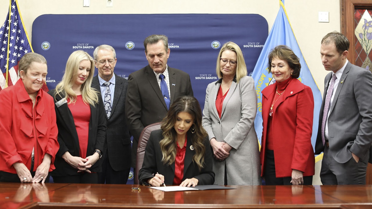 South Dakota Gov. Kristi Noem signed an official proclamation on Jan. 30, 2024 to commemorate the School of Medicine’s 50th anniversary and summarize its successes. Dr. Susan Anderson, Sen. Sydney Davis, Dr. Tim Ridgway, Lt. Gov. Larry Rhoden, USD President Sheila Gestring, Dr. Lori Hansen and Rep. Chris Kassin look on.  South Dakota Gov. Kristi Noem signed an official proclamation on Jan. 30, 2024 to commemorate the School of Medicine’s 50th anniversary and summarize its successes. Dr. Susan Anderson, Sen. Sydney Davis, Dr. Tim Ridgway, Lt. Gov. Larry Rhoden, USD President Sheila Gestring, Dr. Lori Hansen and Rep. Chris Kassin look on.