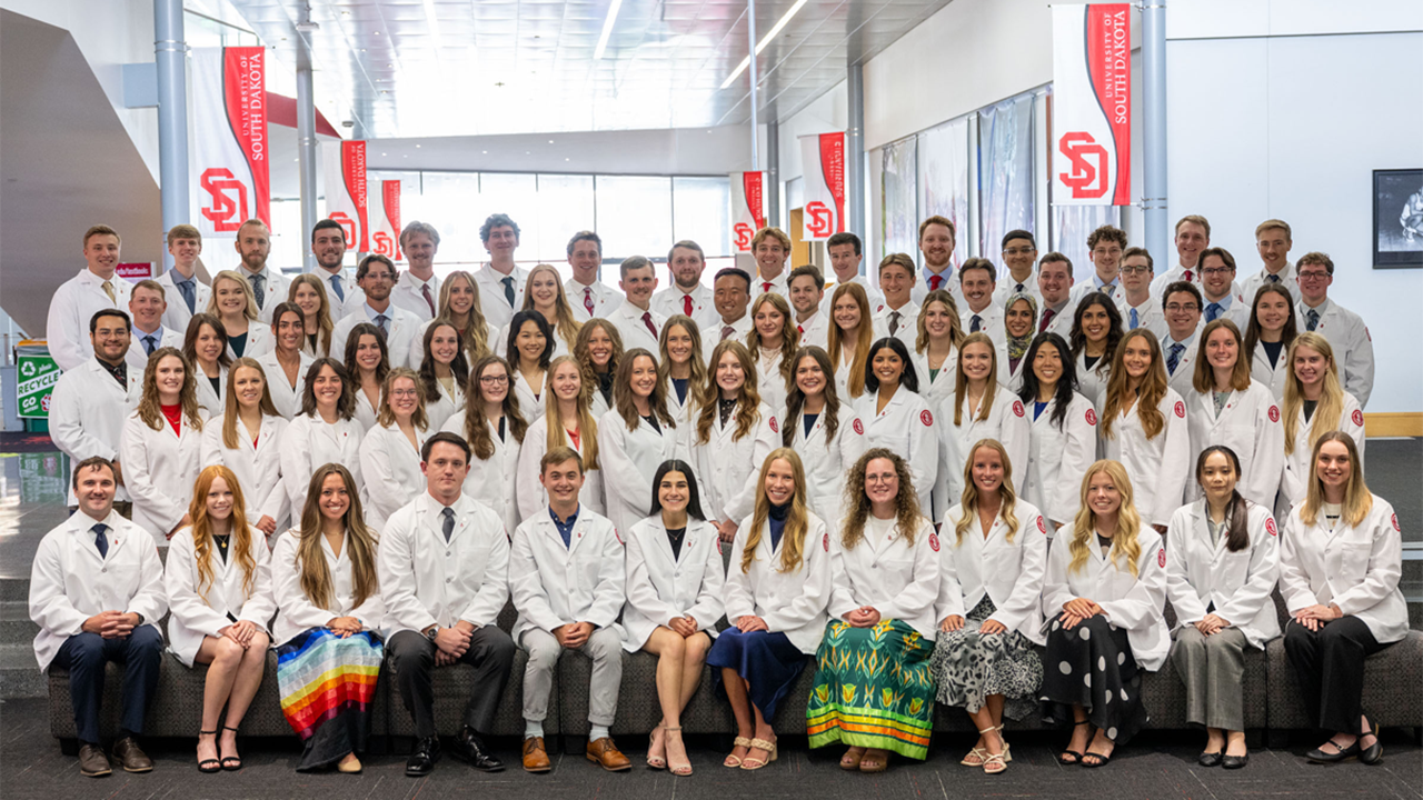 The USD Sanford School of Medicine, Class of 2029, poses for a group photo in their white coats.