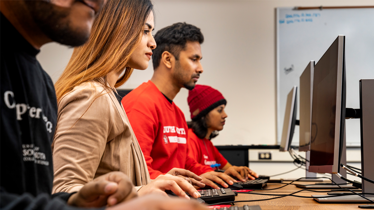 Computer Science students sit in front of their computer monitors and work on assignments.