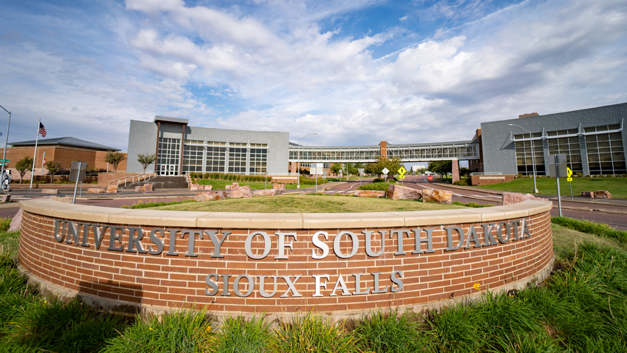 The University of South Dakota - Sioux Falls campus sits behind the USD - Sioux Falls sign.