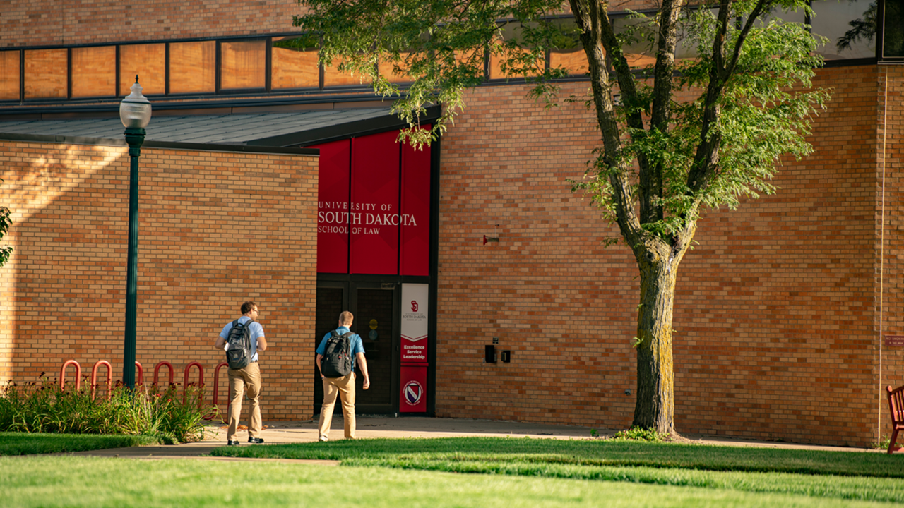 Students walk into the front of the Knudson School of Law building.