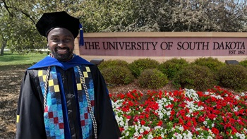 McHale Davis, Ph.D. ’25, educational leadership, stands in front of the USD campus sign.