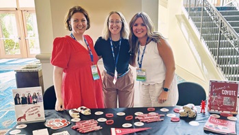 The School of Education faculty and staff poses for a photo behind the USD booth at the National Educators Rising Conference.