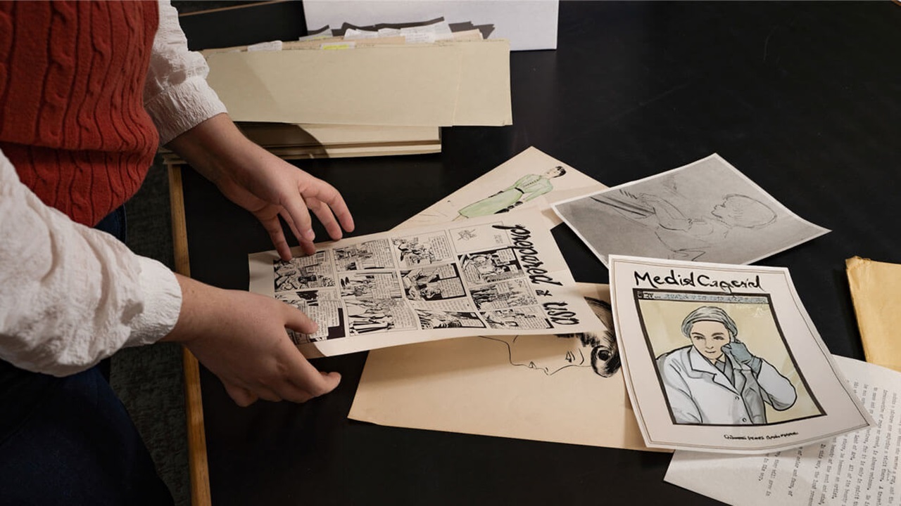 A faculty member stands next to images of graphic medicine.