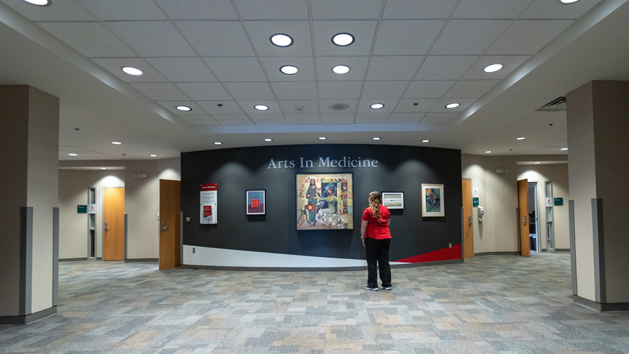 A USD student stands in front of the Artists in Medicine Wall at the Wegner Health Sciences Library.