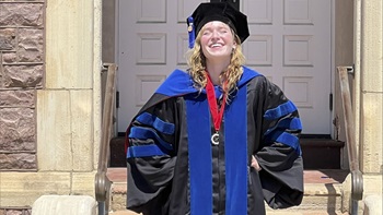 Amelia Harrington standing in front of Old Main wearing their graduation regalia. Amelia Harrington standing in front of Old Main wearing their graduation regalia.