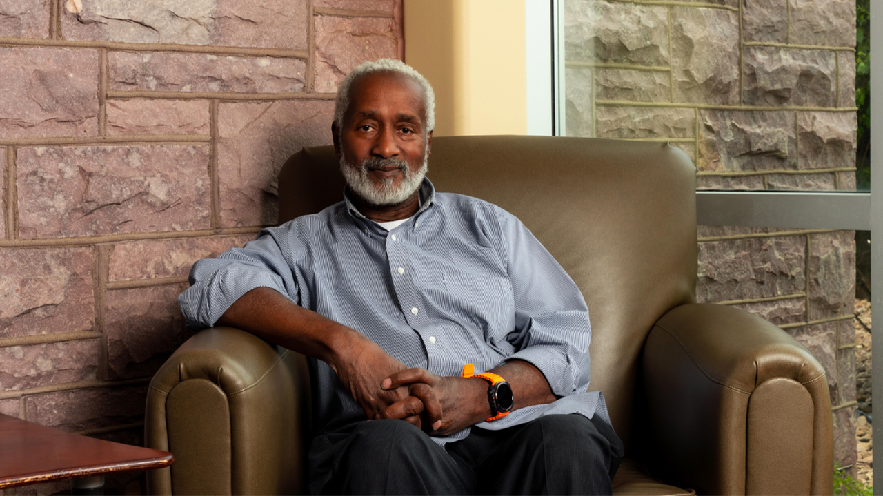 Robin Duncan, Ph.D., lecturer in the University of South Dakota’s Department of Psychology, sits on a green, cushioned chair and poses for a photo.