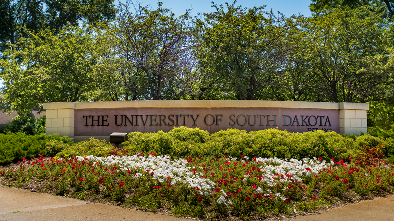 The University of South Dakota sign sits in front of beautiful spring flowers on campus.