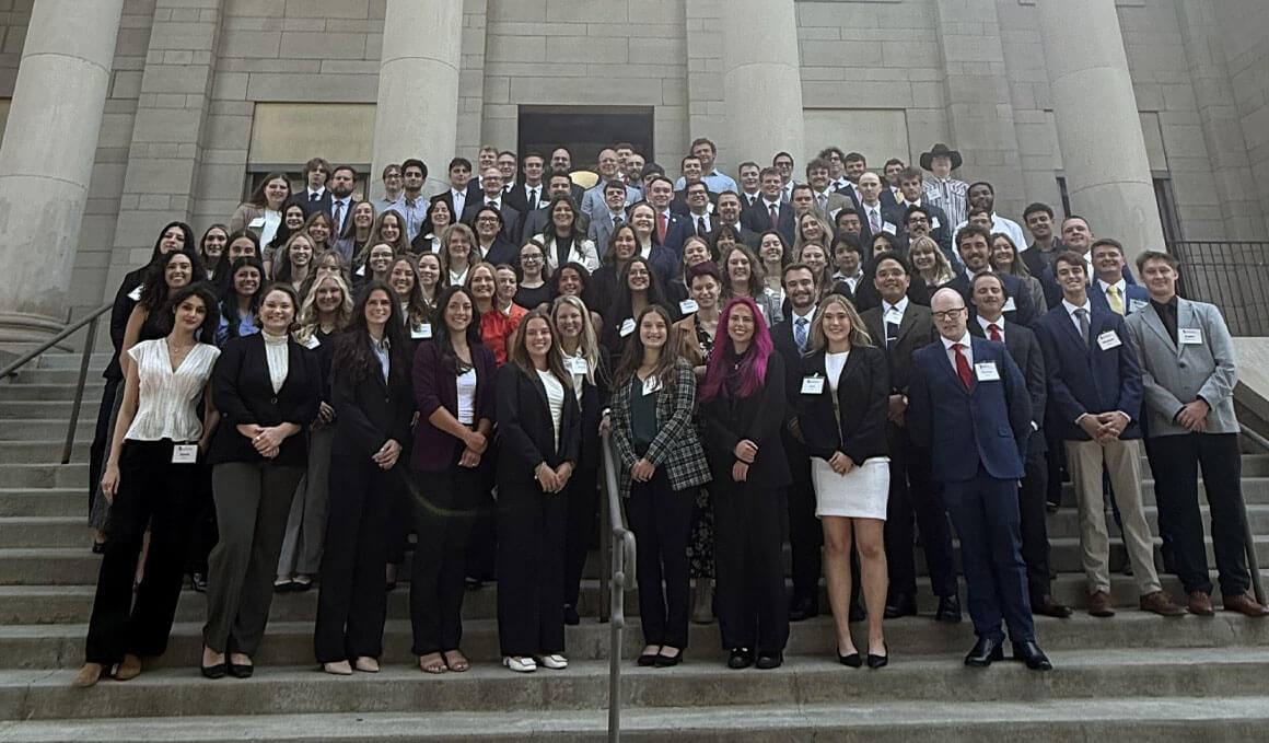 The Knudson School of Law Class of 2029 poses for a class photo on the steps of a building on the USD campus.