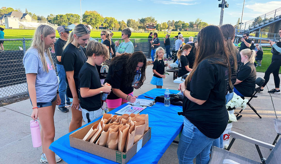 A group of people gather in the concession area of a football complex. They are signing up for an event and speaking to each other.