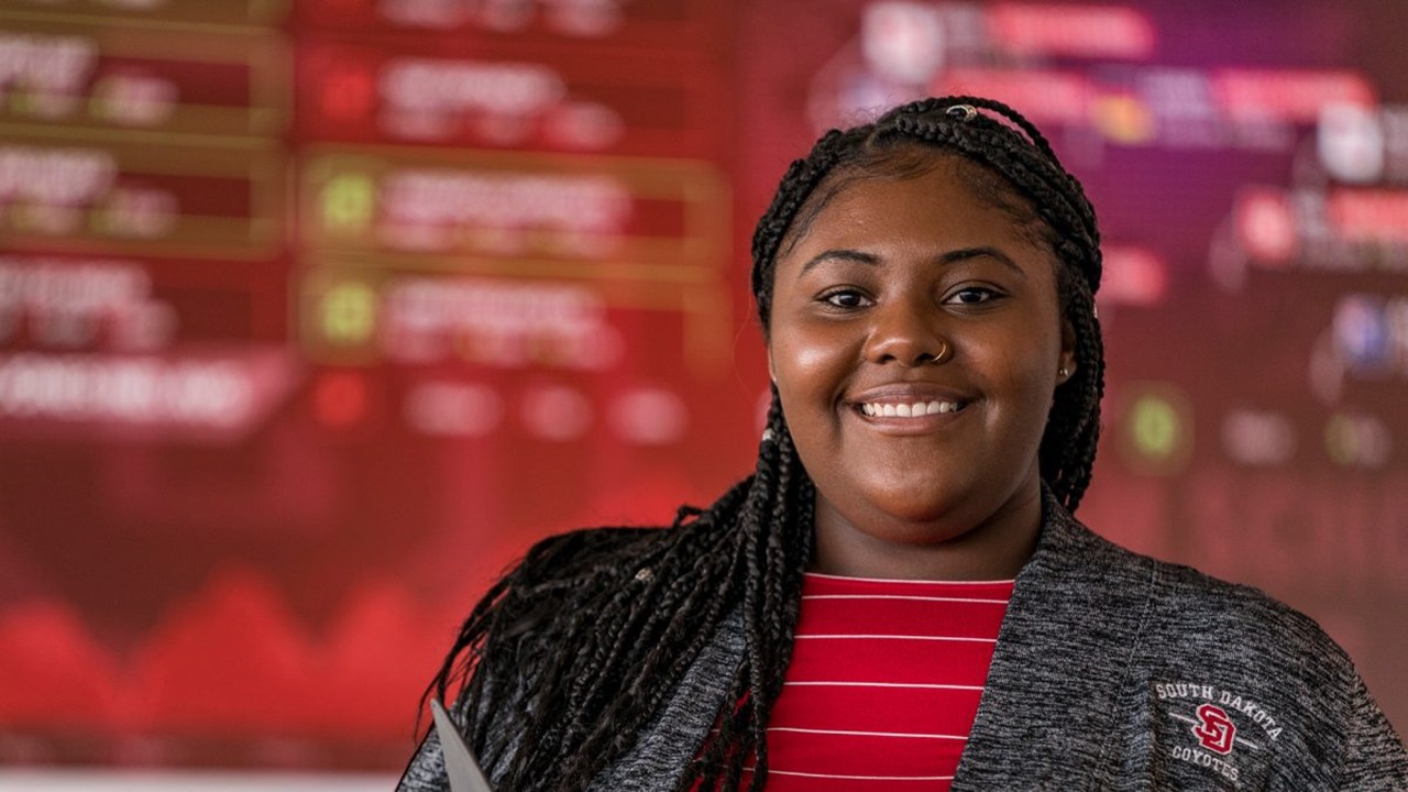 Business student smiles in front of screen.