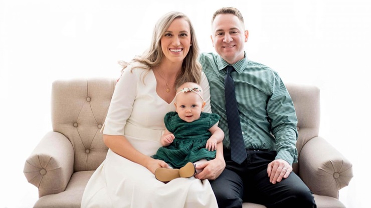 Family sits on couch and smiles for photo.