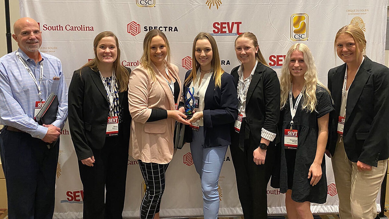 USD business students and their advisor hold an award and pose for a picture.