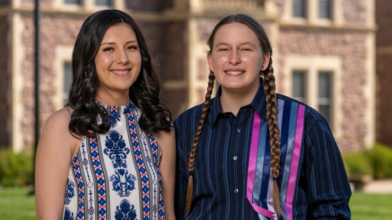 Two students smile in front of Old Main.