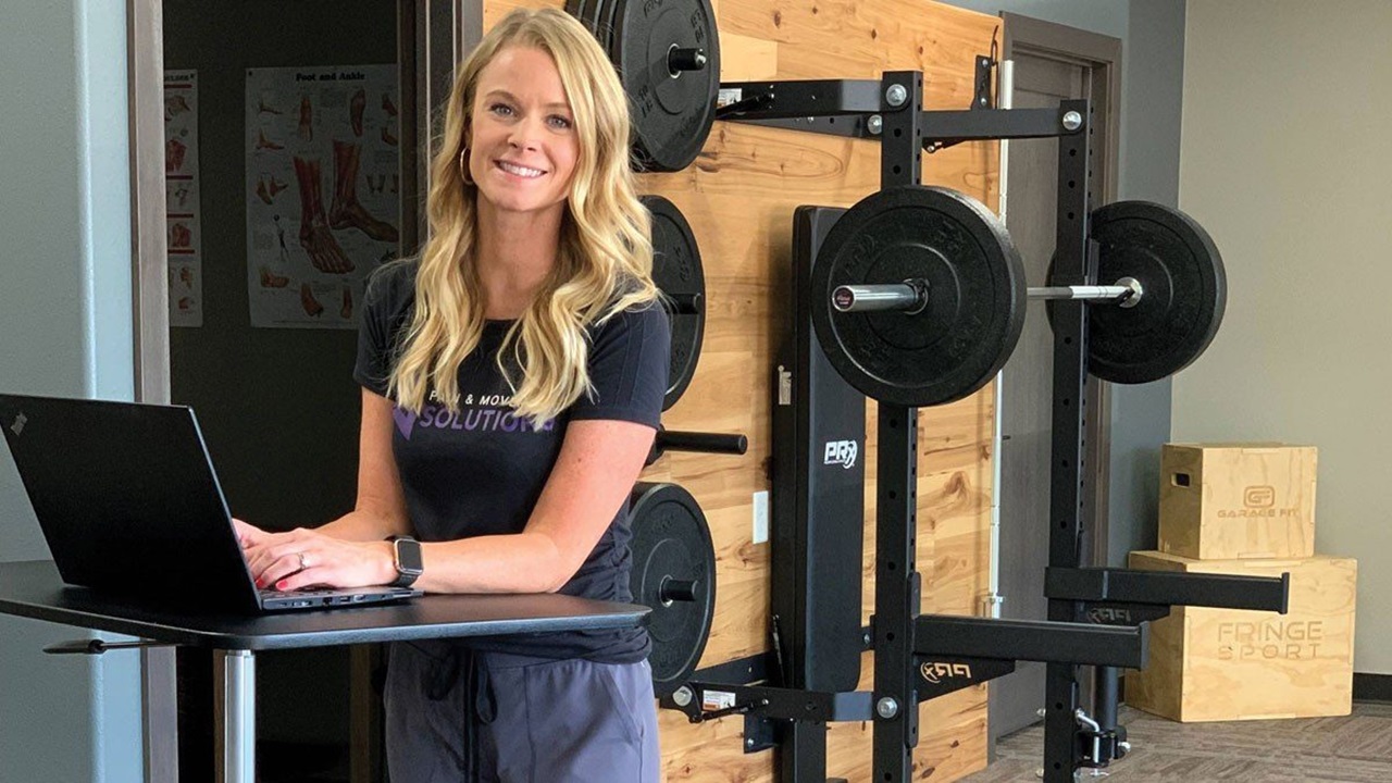 Woman types on a computer in a weight room.