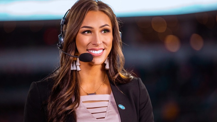 Kelly Stewart smiles with a headset as she reports sports. 