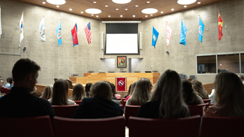 A courtroom full of law students. They all sit forward and face the front of the room.