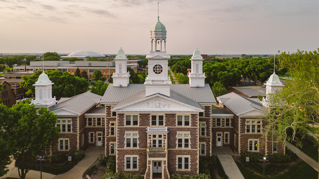 A drone shot of the front of Old Main at sunset.