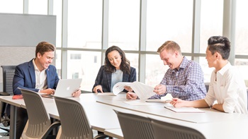 Four business students sit around a table and look at papers.