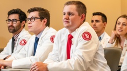 A photo of students in white medical coats in class.