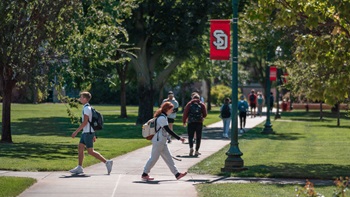 Students walking on campus next to banner