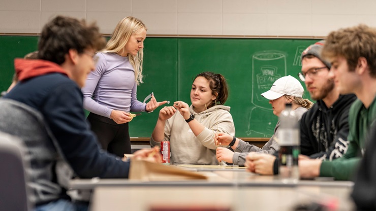 Students working at desk in front of green chalkboard