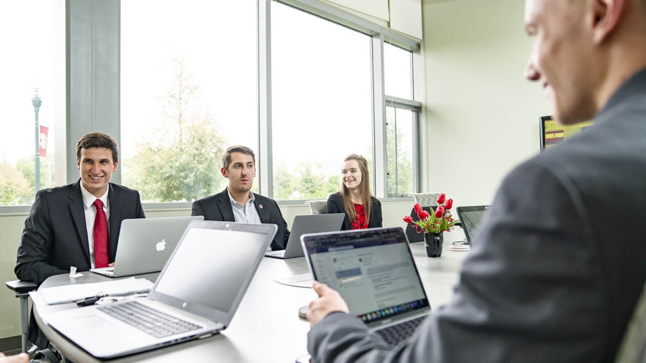 A group of USD Beacom School of Business students sit around a conference table with their laptops. They are collaborating. A group of USD Beacom School of Business students sit around a conference table with their laptops. They are collaborating.